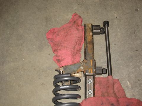 1990 Ford F-250 - Spring compressor tool and coil spring are laid out on a concrete surface with red shop rags.