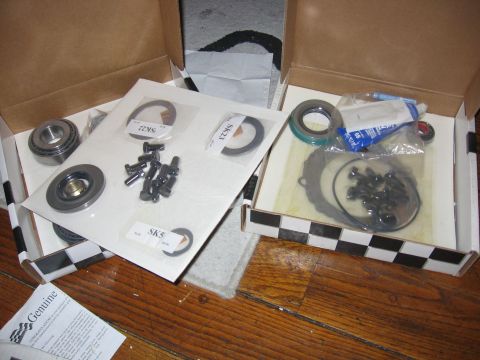 1989 Ford Bronco - Multiple automotive parts kits are displayed in open cardboard boxes on a wooden floor.