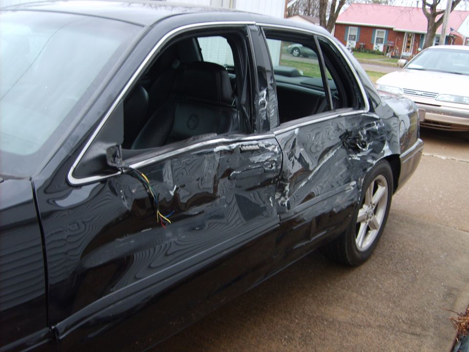 Black sedan with heavy collision damage to passenger-side rear door and quarter panel