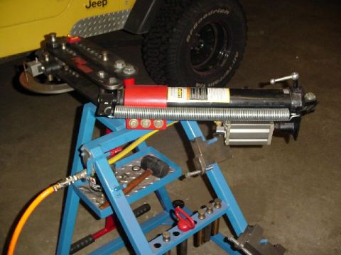 1995 Ford Bronco - A tube bender is shown in front of a yellow Jeep's fender and tire. The "SUPERMOTORS" watermark is visible at the bottom right.
