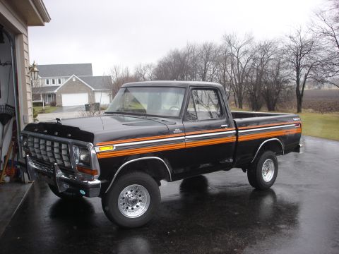 1979 Ford F-150 - This 1979 Ford F-150 pickup truck features a black exterior with distinctive orange racing stripes along its side.