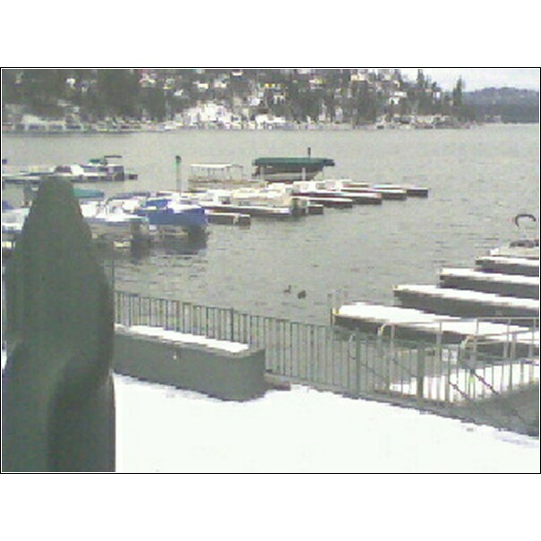 Boats docked on a snowy lake with houses on the hill in the background