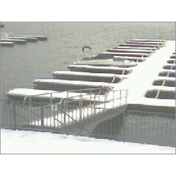 Boats covered in snow docked at a marina with a ramp and railing