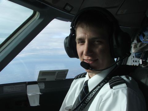1989 Ford Bronco - Pilot smiles for a photo inside the cockpit of an aircraft, with the sky and clouds visible outside.
