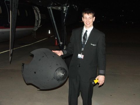 1989 Ford Bronco - Pilot with a detached aircraft part, standing on the tarmac at night.