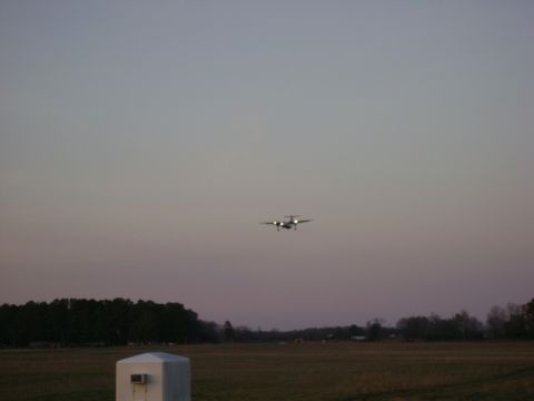 1989 Ford Bronco - Airplane approaching for landing over a field with trees in the background.