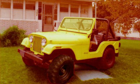 1970 Mercury Cougar - A yellow Jeep CJ is parked in front of a house. The vehicle has a black roll bar and large off-road tires.