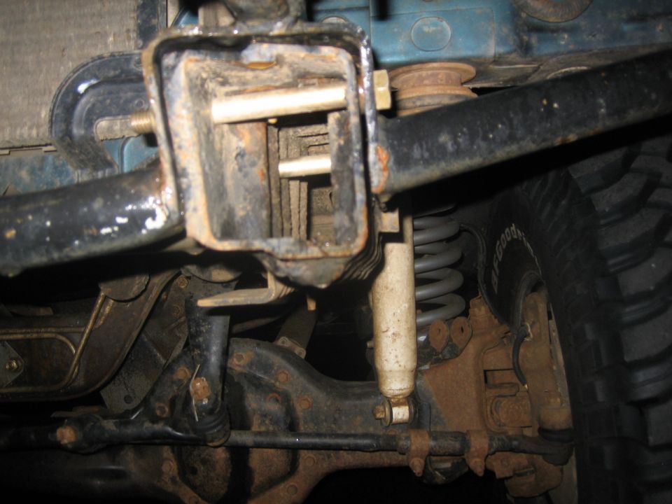 Close-up of a trailer hitch receiver and rear suspension components, including a shock absorber and coil spring