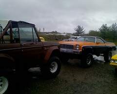 1973 Ford Bronco - Two modified vehicles, a Ford Bronco and a Chevrolet El Camino, sit side-by-side in an outdoor lot.