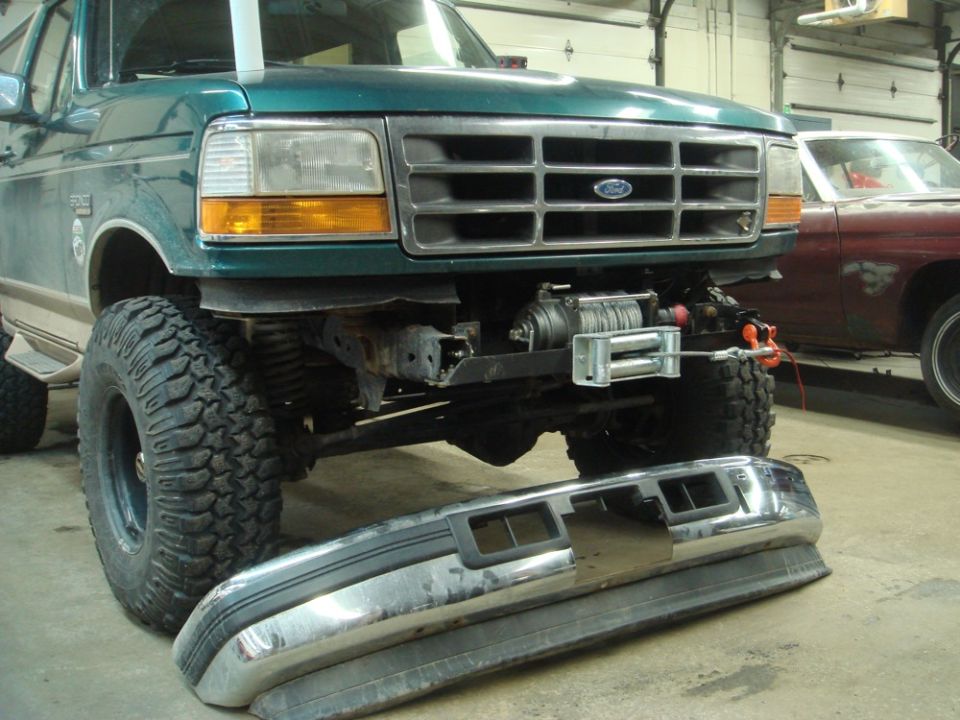 1996 Ford Bronco front end with winch installed, bumper removed. Another vehicle is visible in the background