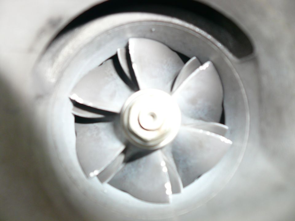 Close-up of a turbocharger compressor wheel with visible blades and a central nut