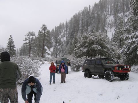 1996 Ford Bronco - Group of off-road vehicles in a snowy forest scene with people present.