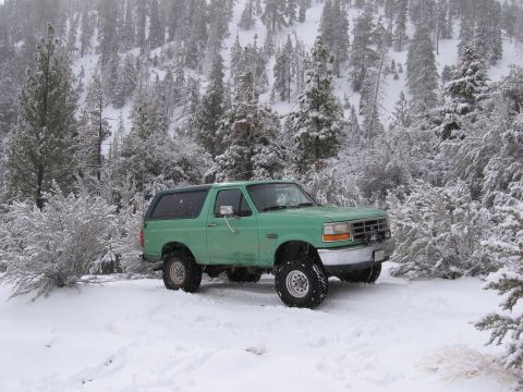 1996 Ford Bronco - A green 1996 Ford Bronco parked in a snowy forest scene.