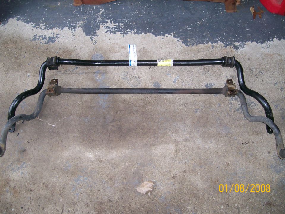 Two black sway bars on a concrete floor. One is thicker and has a yellow label