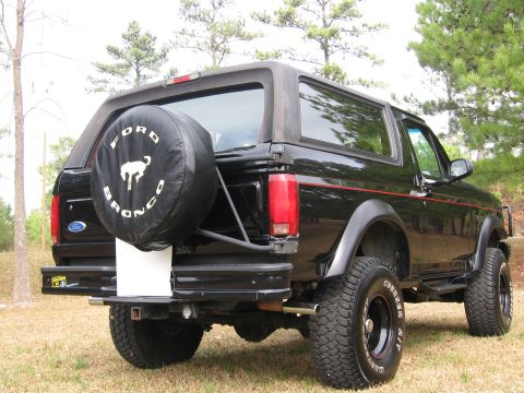 1967 Ford Mustang - Rear view of a black Ford Bronco, a spare tire cover with the "Ford Bronco" logo and horse emblem.