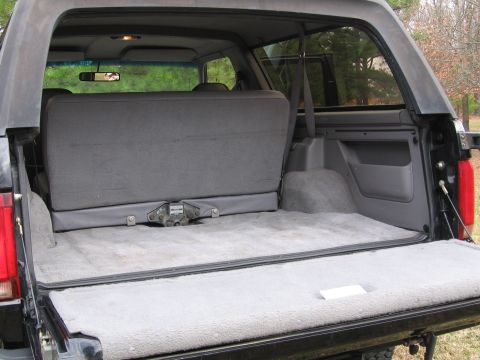 1967 Ford Mustang - The cargo area of a black SUV, likely a Ford Bronco from the 1990s, is shown with gray carpeting and a folded rear seat.