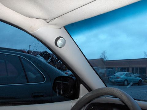 2001 Ford Crown Victoria - A view from inside a vehicle shows a pillar-mounted speaker and a parking lot scene through the window.
