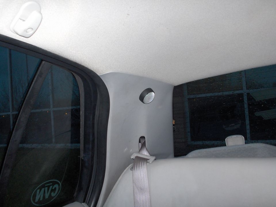Interior rear pillar with a light fixture and seatbelt, viewed from the rear seat