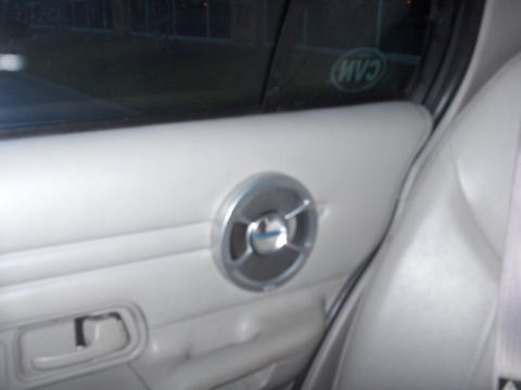2001 Ford Crown Victoria - Close-up of a car's interior door panel, showing a speaker grille and door handle.