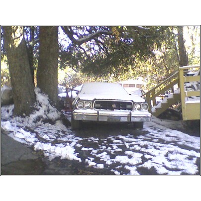 1973 Ford Ranchero - A 1972 Ford Ranchero sits covered in snow, parked outdoors next to trees and a wooden staircase.