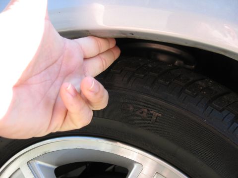2002 Ford Taurus - A hand is shown pressing down on the wheel well above a tire, indicating a potential issue with suspension or clearance.