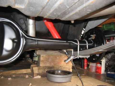1968 Shelby GT500 - Close-up view of a vehicle's rear axle and suspension components, showing leaf springs and a red shock absorber.