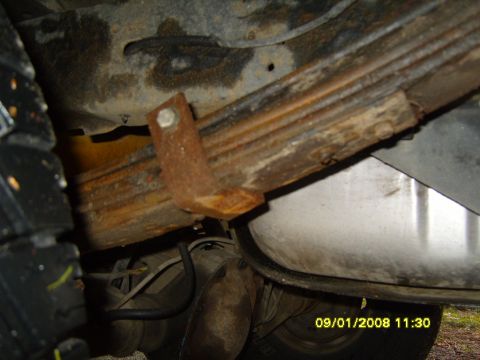 1989 Ford Bronco - Close-up view of a rusty leaf spring clamp and associated suspension parts, with a timestamp visible in the lower right corner.