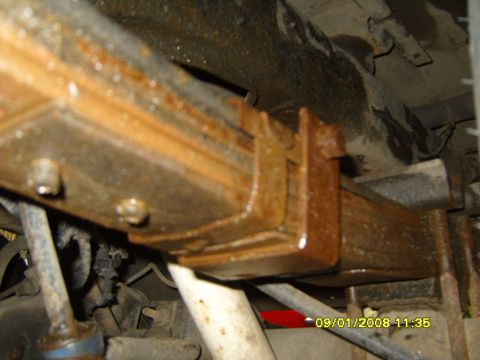 1989 Ford Bronco - Vehicle undercarriage showing a rusty leaf spring clamp and bracket assembly.