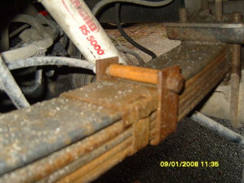 1989 Ford Bronco - Close-up of a vehicle's suspension system, showing a rusty leaf spring and a Rancho RS 5000 shock absorber.