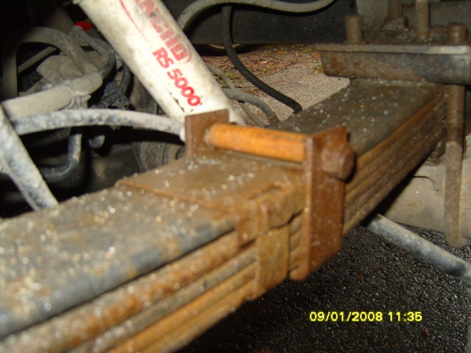 Close-up of rusty leaf spring with a Rancho RS 5000 shock absorber