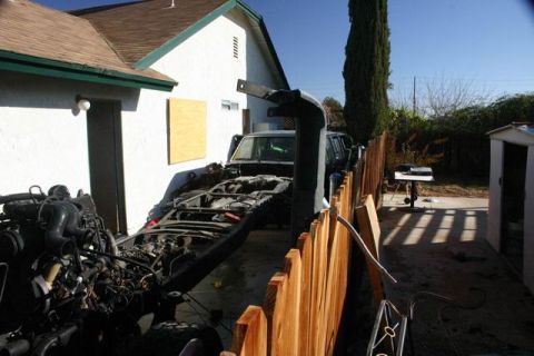1991 Ford Bronco - A vehicle's chassis and engine are disassembled in a residential yard, suggesting a project in progress.