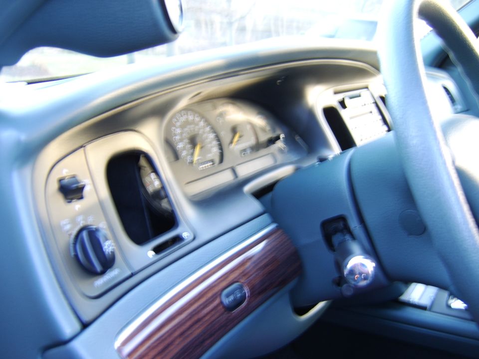 Car dashboard with gauge cluster, dial controls, and wood-grain trim panel