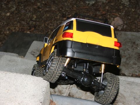 1996 Ford Bronco - A yellow SUV navigates a rocky, uneven terrain, with its rear wheels on concrete blocks.