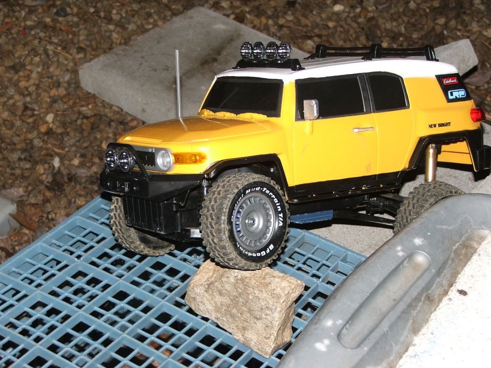 Yellow toy FJ Cruiser with roof lights on blue grate