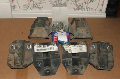 1991 Ford Crown Victoria LTD - A collection of engine mounts and assorted hardware, along with a box of NAPA mini lamp bulbs, are laid out on a cardboard surface.