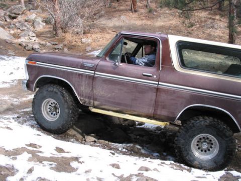1979 Ford Bronco - 1979 Ford Bronco navigating a rocky trail with patches of snow.