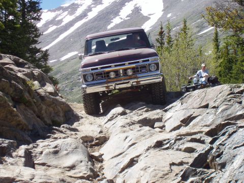 1979 Ford Bronco - A 1979 Ford Bronco navigates a challenging rocky terrain on a mountain pass.