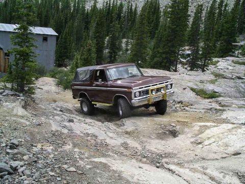 1979 Ford Bronco - This 1979 Ford Bronco navigates a challenging rocky trail in a mountainous, forested area.