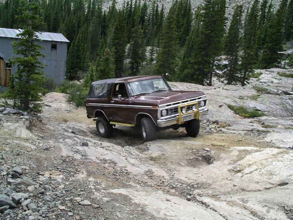 Brown 1979 Ford Bronco 4x4 off-roading on rocky terrain