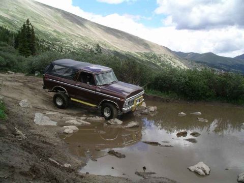 1979 Ford Bronco - Ford Bronco tackles a challenging off-road obstacle on a mountain trail.