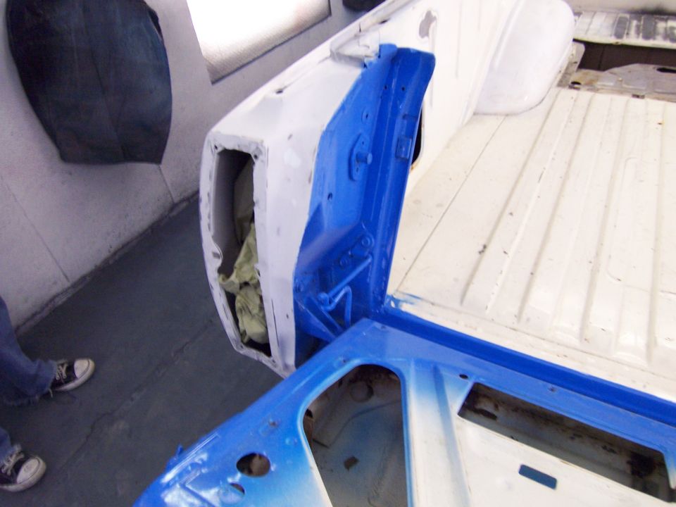 Ranchero body shell in paint booth with door jamb and inner door painted blue, rest in white primer