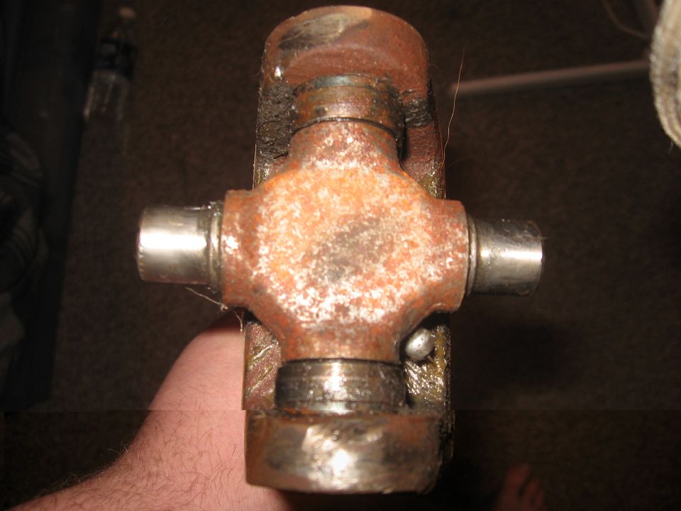 Close-up of a rusty universal joint with a hand holding it