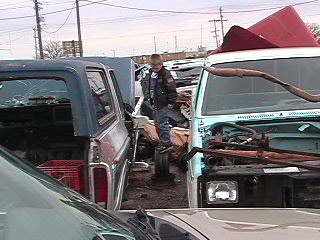 1979 Ford Bronco - Two vehicles are visible in a junkyard setting, with a person standing between them.