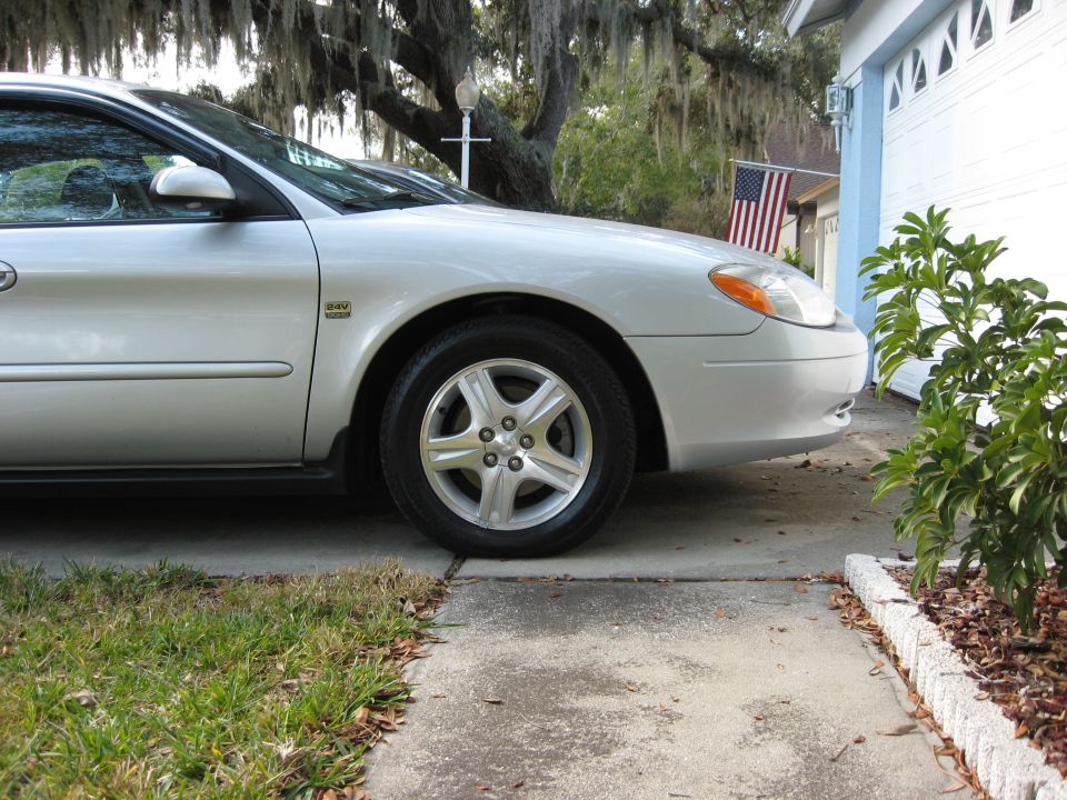 Silver sedan parked on concrete driveway, front passenger side visible