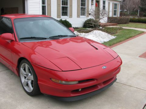 1993 Ford Probe - A red 1993 Ford Probe is parked in a driveway with a house in the background.