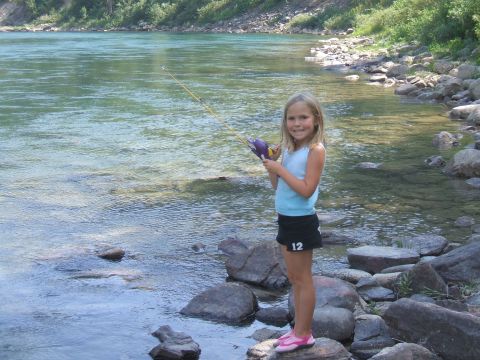 1974 Ford Ranchero - A young girl fishes from the rocky bank of a river on a sunny day.
