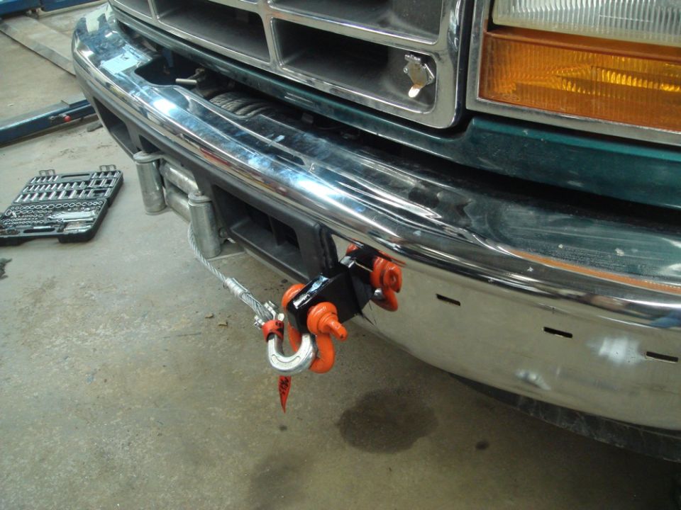 Green Ford truck front bumper with chrome grille, orange winch hook, and a toolbox nearby