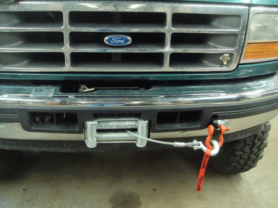 1996 Ford Bronco front grille with a winch installed on the bumper, cable attached to an orange shackle