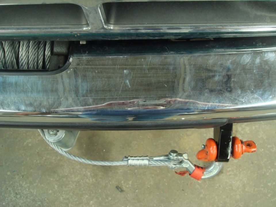 Winch cable attached to tow hook on vehicle bumper