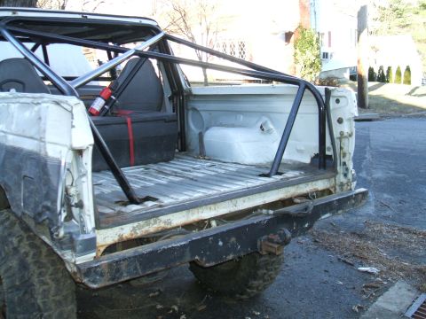 1995 Ford Bronco - Rear view of a white 1995 Ford Bronco modified with a custom roll cage and equipped with a fire extinguisher.